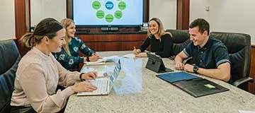 Individuals are seated around a conference table, engaged in a collaborative meeting at Almas Tower, Dubai 