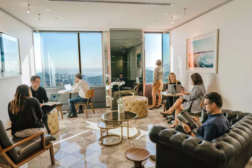 Professionals networking in a bright lounge with city views at a premium Servcorp virtual office location.