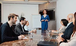 A woman leading a business presentation in a meeting room at 10 Avenue Kléber, surrounded by professionals in a premium setting.